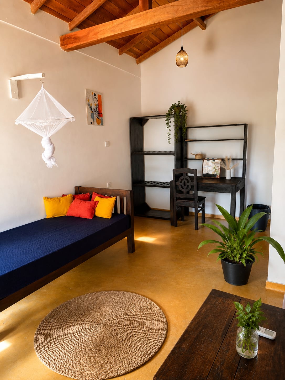Interior corner with daybed, cushions, desk and hanging mosquito net under wooden beams