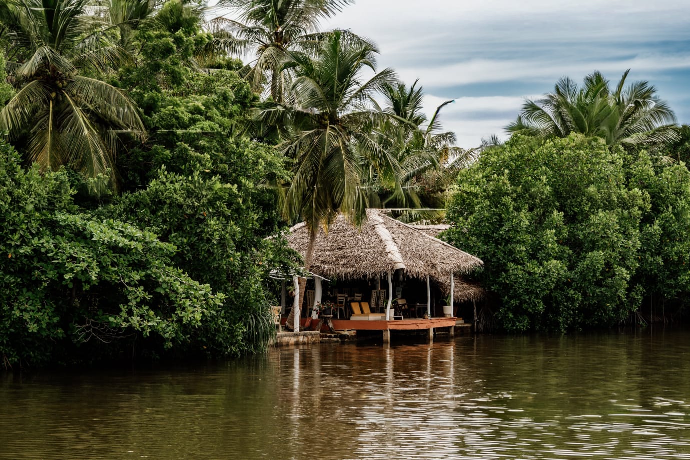 Thatched lagoon-side cabana at Ginger Harmony Tangalle, surrounded by mangroves and coconut palms
