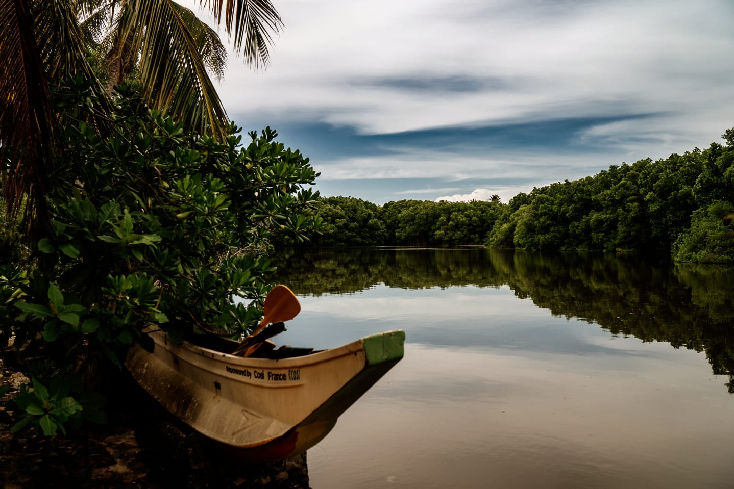 A wooden canoe resting at the edge of the quiet Tangalle lagoon