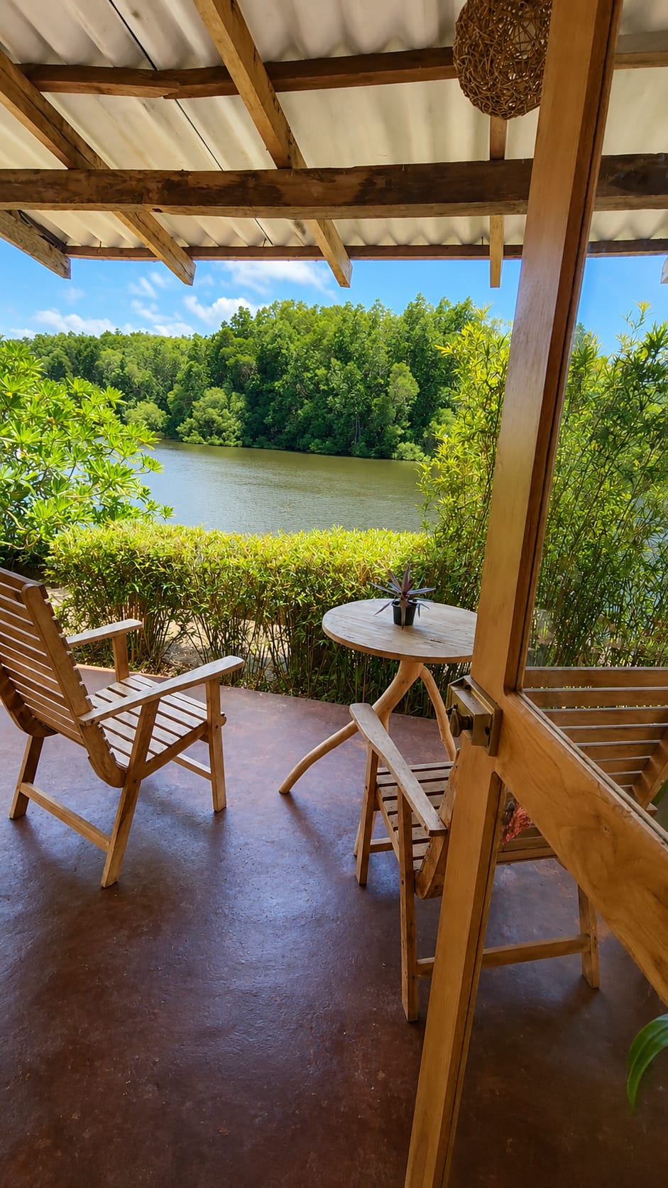 Shaded terrace with wooden seating looking out over the lagoon and mangroves